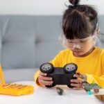 Little girls having fun in a workshop coding robot car